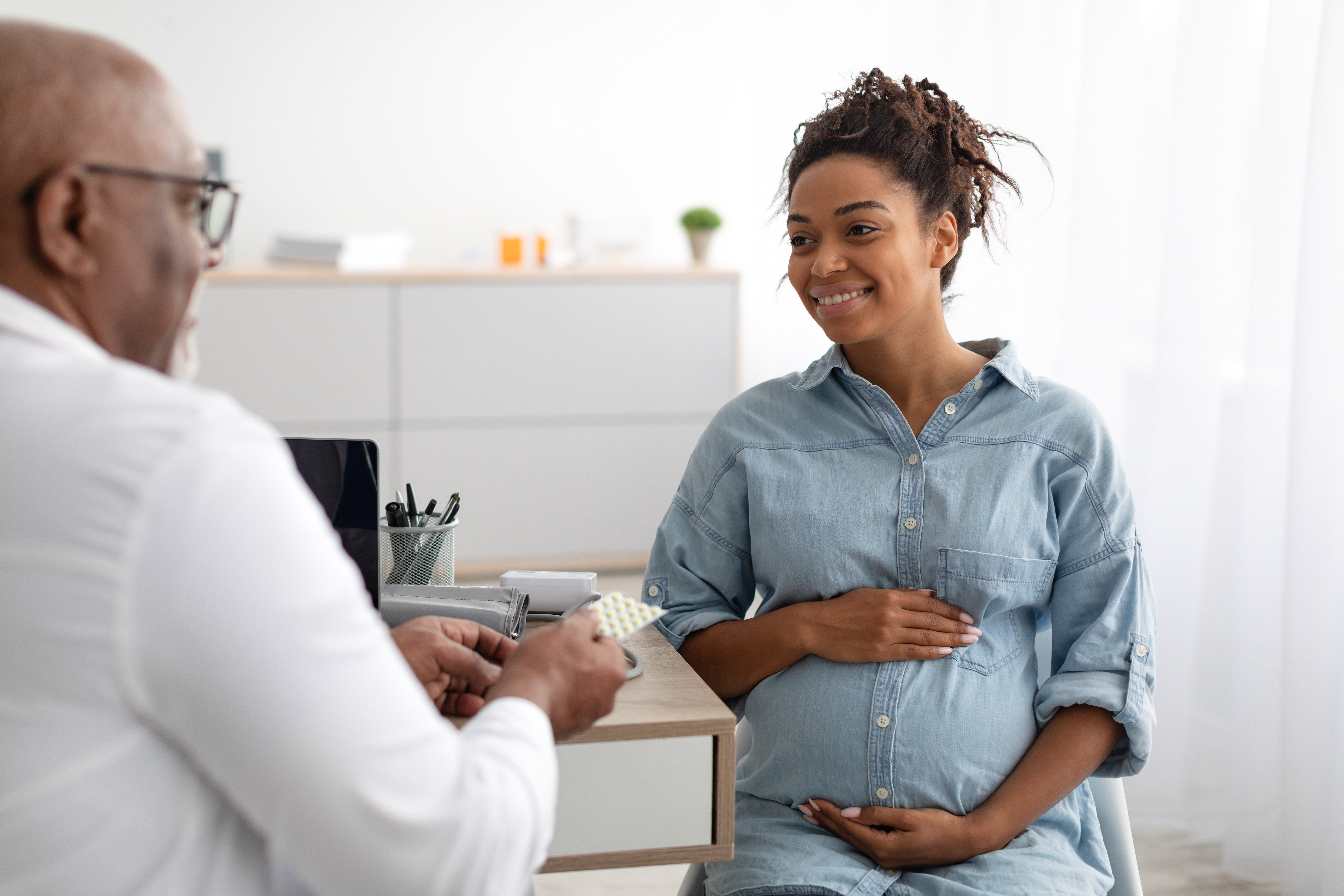 A pregnant person discusses tablet medicine with their doctor during an appointment.