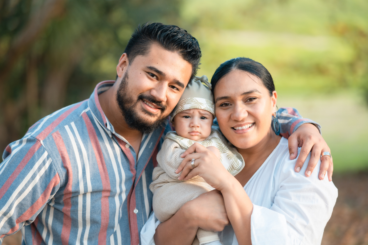 A family with two parents and a newborn baby enjoys an afternoon in a park