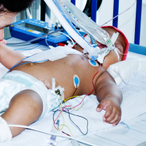 A NICU baby receives a kiss on the hand from its parent.