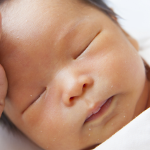 A NICU caregiver places their hand on a NICU baby's forehead.